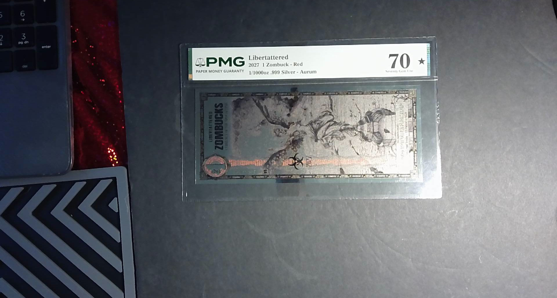 2027 Libertattered 1 Zombuck Red Aurum PMG 70★ – 1/1000 oz .999 Silver